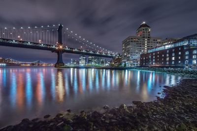 Illuminated manhattan bridge over east river against in city