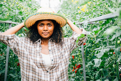 Portrait of young woman standing against plants