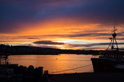 Sailboats moored on sea against sky during sunset