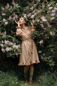 Statue of woman standing by flowering plants