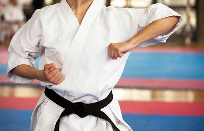 Midsection of man practicing karate on carpet