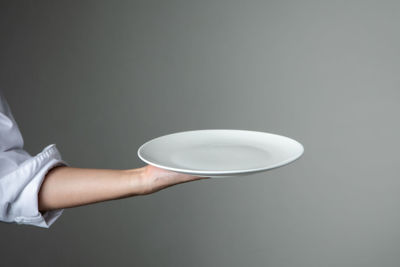 Close-up of hand holding tea cup over white background