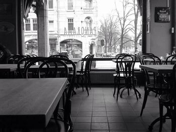 Empty chairs and tables at sidewalk cafe in city