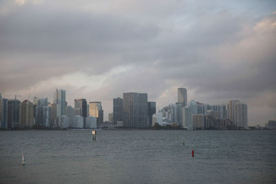 Sea by cityscape against sky