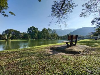 Bench by lake against sky