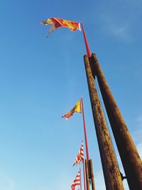 Low angle view of flags flying against sky