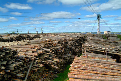 Stack of wood by sea against sky