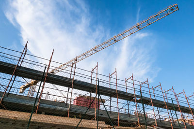 Low angle view of cranes at construction site against sky