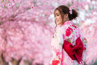 Woman standing by pink flower