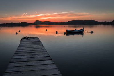 Pier on lake against sky during sunset