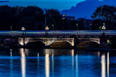 Illuminated bridge over river against sky at night