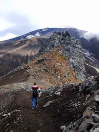 Rear view of person on rock against sky