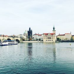 View of buildings by river against sky in city