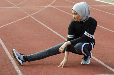 Full length of athlete wearing hijab while training on sports track