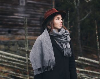 Portrait of beautiful young woman standing against brick wall