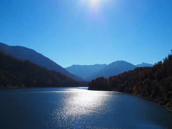 Scenic view of lake and mountains against blue sky