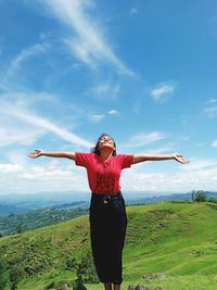 Young woman with arms outstretched standing on mountain