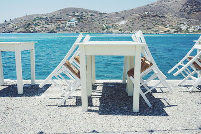 Chairs on beach against blue sky