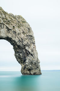 Rock formation in sea against clear sky