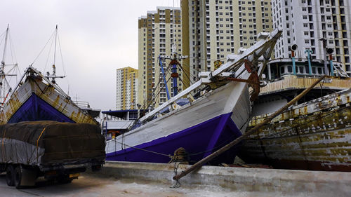 Boats moored at harbor against sky