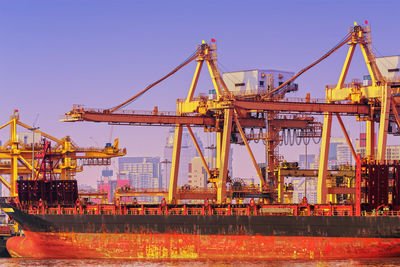 Cranes at commercial dock against clear sky