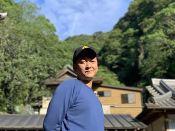 Portrait of young man standing against trees