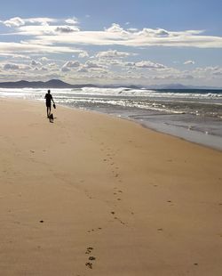 Rear view of child on beach against sky