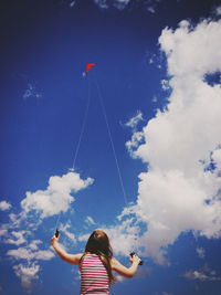 Low angle view of girl flying kite against sky