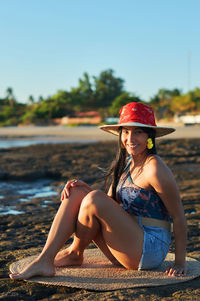 Portrait of woman wearing hat sitting on beach