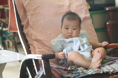 Full length of cute baby girl sitting on sofa