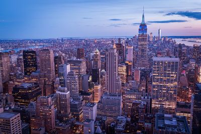 Aerial view of city lit up against sky