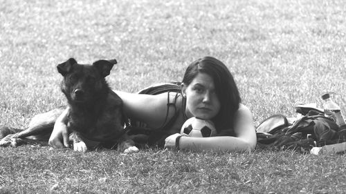 Portrait of young woman with dog on grassy field