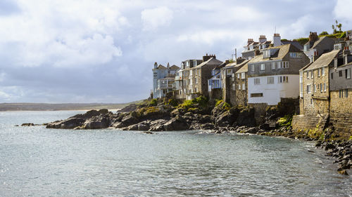 Buildings by sea against sky