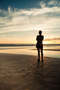 Silhouette man standing on beach against sky during sunset