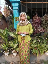 Portrait of woman standing against plants