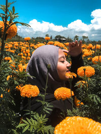 Young woman wearing hijab shielding eyes amidst flowers