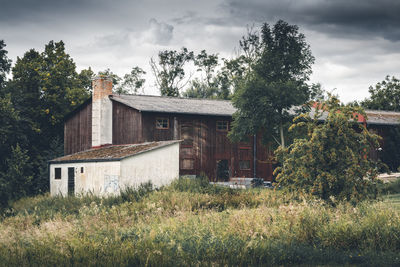 House and trees on field against sky