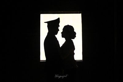 Silhouette man and woman standing against black background