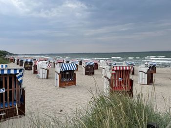 Hooded chairs on beach against sky