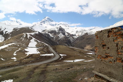 Road amidst snowcapped mountains against sky