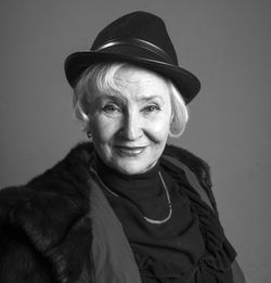 Close-up portrait of confident senior woman against gray background