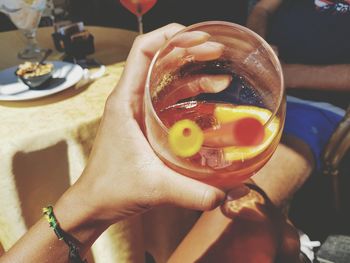 Cropped hand of mid adult woman holding drink at restaurant