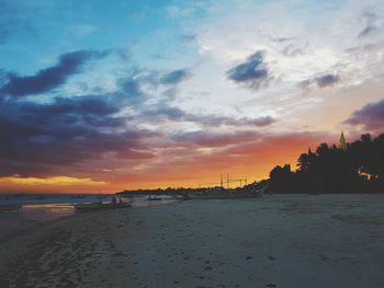 Scenic view of beach against sky at sunset
