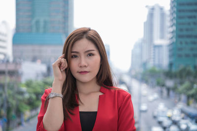 Portrait of beautiful woman standing against city buildings