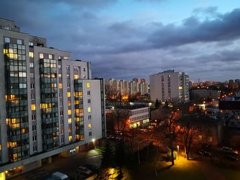 Illuminated buildings in city against sky at dusk