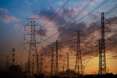 Low angle view of silhouette electricity pylon against sky during sunset