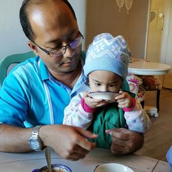 Close-up of father sitting with daughter having food at table