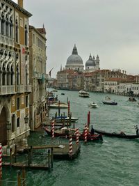 Boats in grand canal italy by buildings against sky