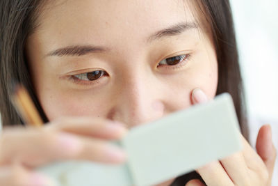 Close-up of young woman touching skin while looking at mirror