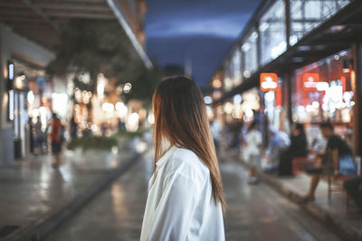 Rear view of woman standing in city at night